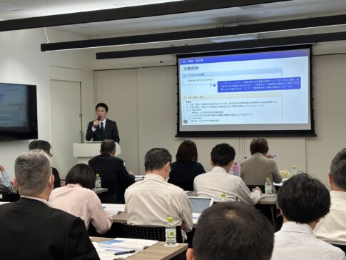 会議室でスーツ姿の講師が講演中